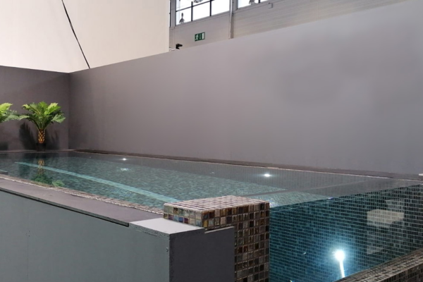 Mosaic swim spa with glass wall overflow